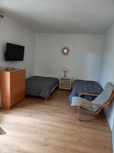 - une chambre avec 2 lits, une chaise et une télévision dans l'établissement Appartement 30m2 proche gorge du verdon et cure thermale de Gréoux, à Gréoux-les-Bains