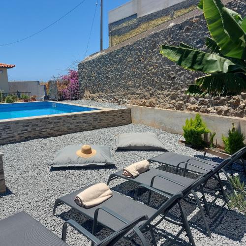 a patio with two lounge chairs and a pool at Maria's House in Câmara de Lobos