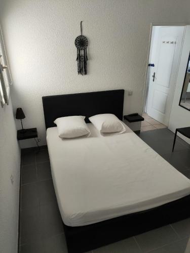 un lit blanc avec deux oreillers dessus dans l'établissement Petit nid d amour, à Argelès-sur-Mer