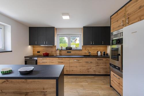 a kitchen with wooden cabinets and a black counter top at Wellness Chalupa Hayek in Česká Ves