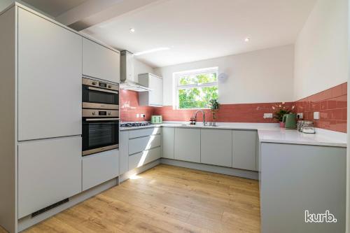 a white kitchen with white cabinets and a window at Fern Cottage - 5 bedroom House free Parking in Nottingham