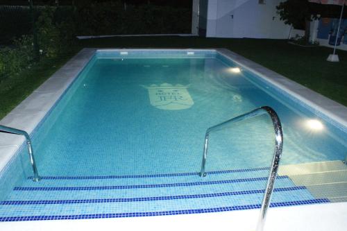 a swimming pool with a sign in the water at Hotel Juan Francisco in Güéjar-Sierra