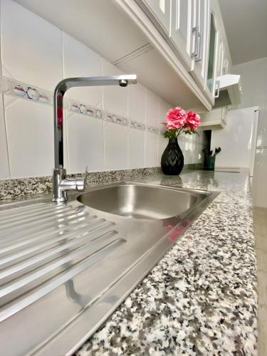 a sink in a kitchen with a vase with pink flowers at Casa de Silvia in Arrecife