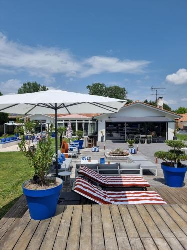 un patio avec des chaises et des parasols sur une terrasse en bois dans l'établissement La Parenthèse du Las, Maison d'hôtes avec Piscine et Spa, à Saint-Jean-dʼIllac