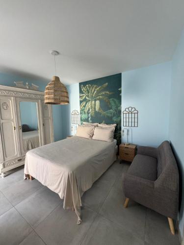 une chambre avec un grand lit et une chaise dans l'établissement Villas Ambiance 21 Elégance Méditerranéenne à Portiragnes entre Terre et Mer Villa Séréna, à Portiragnes