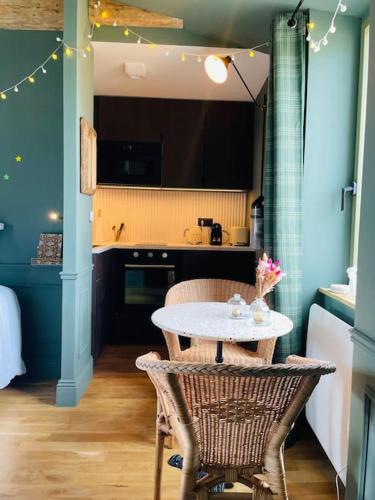 une cuisine avec une table et des chaises dans une pièce dans l'établissement Suite bord de mer - Balnéo et sauna, à Bernières-sur-Mer