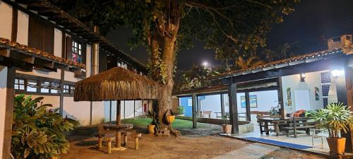 a building with a table and a tree at night at Pousada dos Veleiros in Nova Almeida