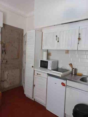 une petite cuisine avec des armoires blanches et un micro-ondes dans l'établissement les pieds dans l'eau, à La Seyne-sur-Mer