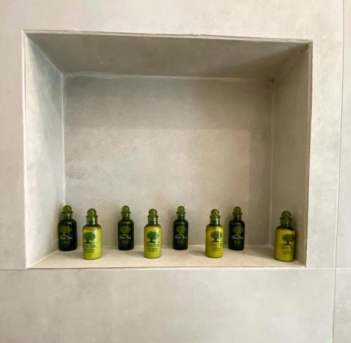 a row of green bottles sitting on a shelf at Nohēme Luxury Suites in Vourvoulos