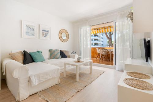 ein weißes Wohnzimmer mit einem weißen Sofa und einem Tisch in der Unterkunft WELCS APARTAMENTO 165 PDA con piscina in Platja  d'Aro