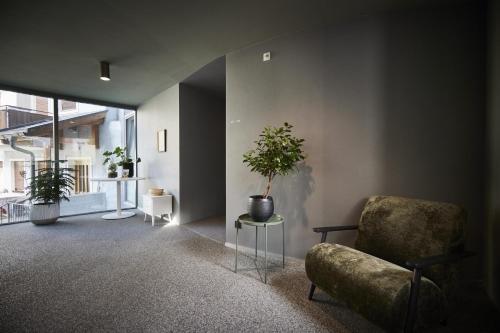 a living room with a chair and a potted plant at Bettstadt Apartments in Vipiteno