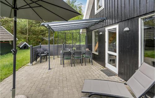 a patio with a table and chairs and an umbrella at Holiday Home Koubjerg Iii in Toftum