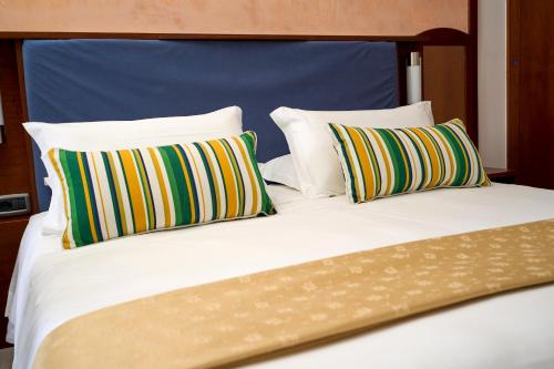 a bed with three pillows and a blue head board at Hotel Graal in Ravello