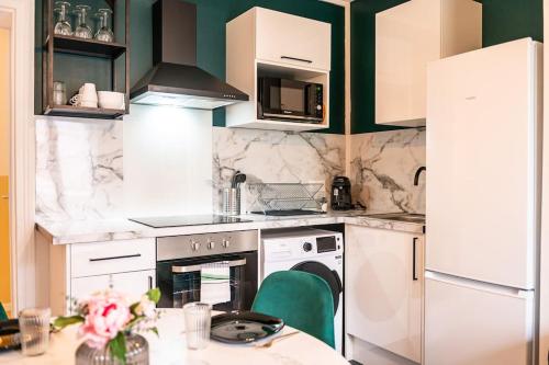 - une cuisine avec des appareils électroménagers blancs et des murs verts dans l'établissement Appartement Rénové, à Rouen