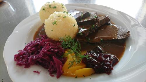 a plate of food with meat and vegetables on it at Pension Philippsreut "Zum Pfenniggeiger" Am Goldsteigwanderweg in Philippsreut