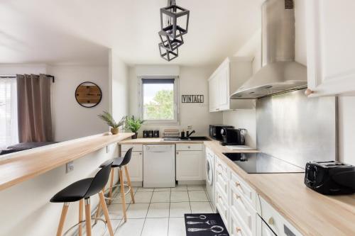 a kitchen with white cabinets and bar stools at L'îlot Zen- Idéal pour famille-Groupe-Pro-Double Parking-highwifi-Aeroport Orly 8min-Paris30min in Fresnes