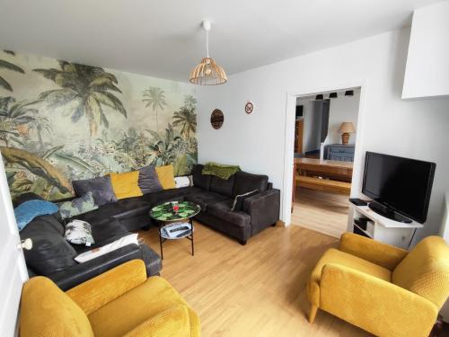 a living room with a black couch and yellow chairs at MER 12 à 14 pers L'Aiguillon sur mer in LʼAiguillon-sur-Mer