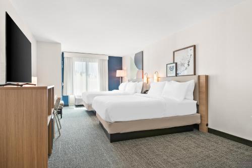 a hotel room with three beds and a flat screen tv at Spark By Hilton Hummelstown Hershey in Hummelstown