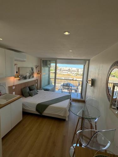 Cet appartement comprend une chambre avec un lit et une cuisine avec un balcon. dans l'établissement Village Naturiste Héliopolis FGH, au Cap d'Agde