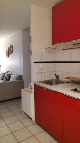 - une cuisine avec des placards rouges et blancs et un canapé dans l'établissement Joli T2 à Montpellier, à Montpellier