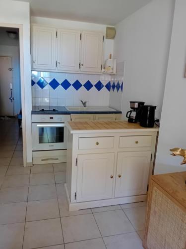 une cuisine avec des placards blancs et du carrelage bleu sur le mur. dans l'établissement face a la mer, à La Londe-les-Maures