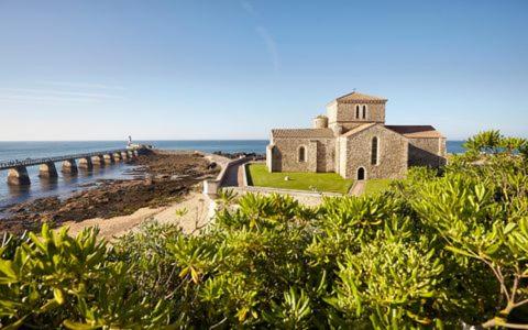un vieux bâtiment sur la plage avec un pont dans l'établissement Les Baleinières Les Sables d'Olonne La Chaume, à Les Sables-dʼOlonne