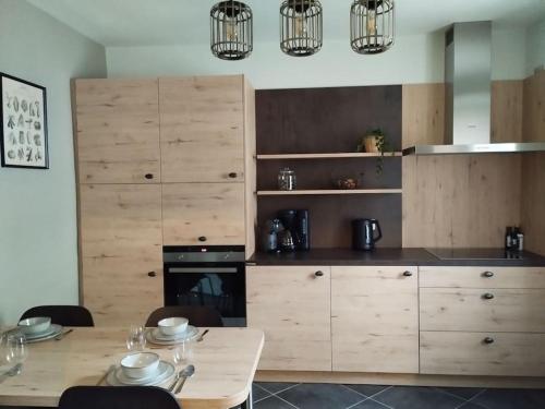 une cuisine avec des armoires en bois et une table avec des chaises dans l'établissement Le Pré Ducrot, à Saint-Michel