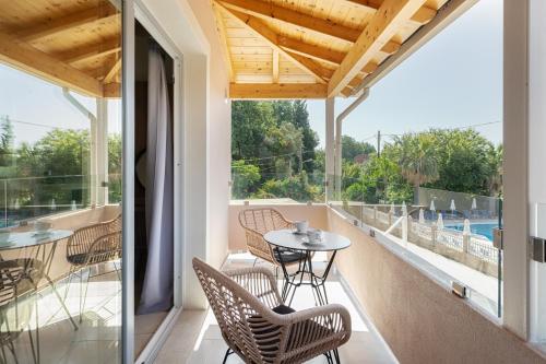 a balcony with a table and chairs and a view of a pool at Dominoes Corfu in Ýpsos