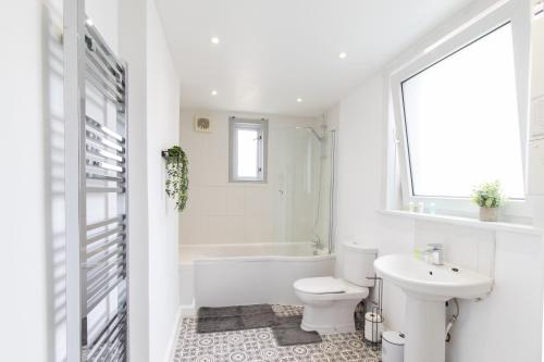 a white bathroom with a toilet and a sink at Open Mind Property - HotTub, 8 Beds & 2 Car Spaces in Portsmouth