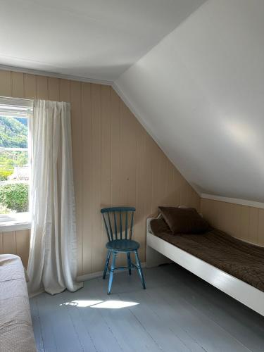 a bed and a chair in a room with a window at Veslegarden in Lærdalsøyri