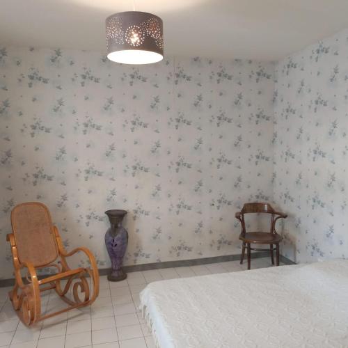 a bedroom with a bed and two chairs and a lamp at Maison avec superbe terrasse tropézienne in Adissan