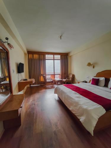 a bedroom with a large bed and a large window at Hotel Arohi in Vashisht