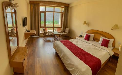 a bedroom with a large bed and a table with chairs at Hotel Arohi in Vashisht
