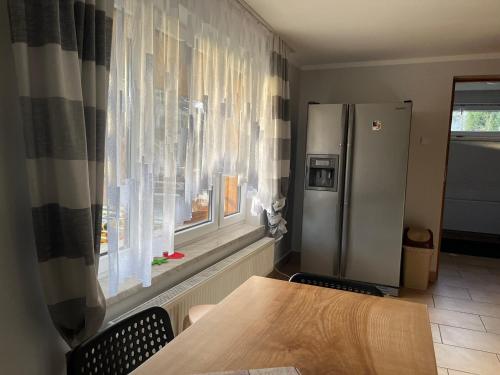 a kitchen with a table and a refrigerator and a window at Domek przy szlaku in Rajcza