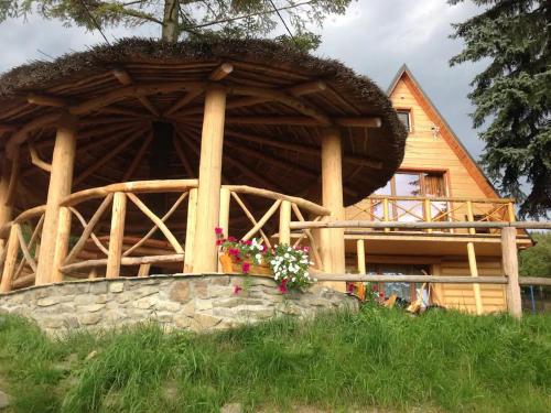 a log cabin with a thatched roof and flowers at Domek przy szlaku in Rajcza