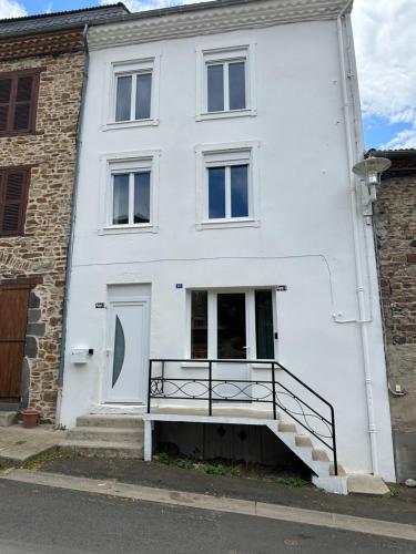 a white house with a staircase in front of it at Chez romain in Massiac