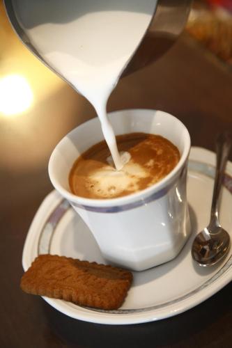 a cup of coffee on a plate with a spoon at Hotel Houston in Rimini
