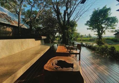 two benches sitting on a wooden deck with trees at BREATHE - Rice Valley in Ban Pa Lan