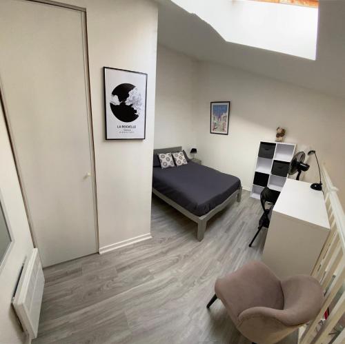 une chambre avec un lit et une chaise dans une pièce dans l'établissement La Rochelle - Tout confort pour 4 personnes proche vieux port, à La Rochelle