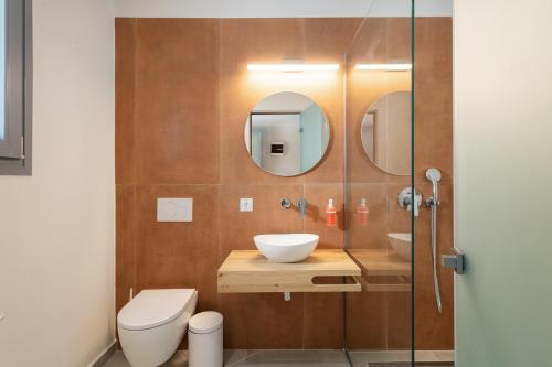 a bathroom with a sink and a toilet and a mirror at Dominoes Corfu in Ýpsos