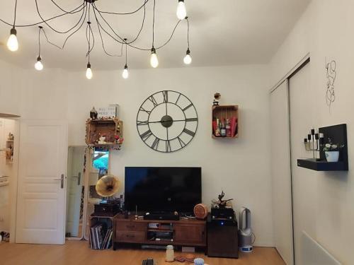 - un salon avec une télévision et une horloge murale dans l'établissement Appartement vintage, à Pontoise