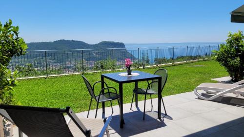 a table with chairs and a vase of flowers on a patio at Appartamenti Annachiara in Costermano sul Garda