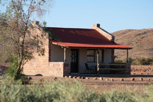 a small brick house with a red roof at Duwisib Guest Farm in Duwisib