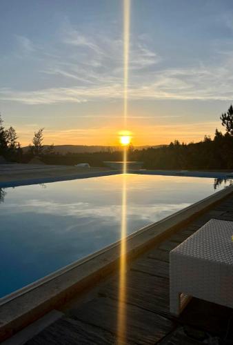 a pool with the sun setting over the water at Casa de Pedra in Pedrógão Grande