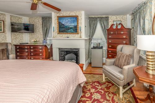a bedroom with a bed and a chair and a fireplace at Holiday Guest House Bed & Breakfast in Wells