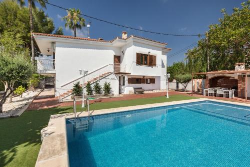 a villa with a swimming pool in front of a house at Villa Paraíso - Piscina Playa Barbacoa Wifi in San Juan de Alicante