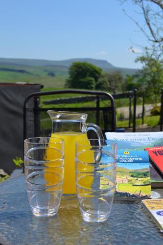 a jug of orange juice and two glasses on a table at Ashes Farm - Ingleborough Barn Cottage, with 3 peaks views, near Settle in Settle
