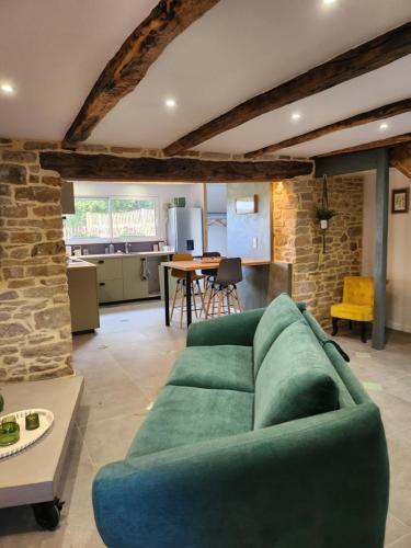 a living room with a green couch and a kitchen at Gîte du clos marty in Sébrazac