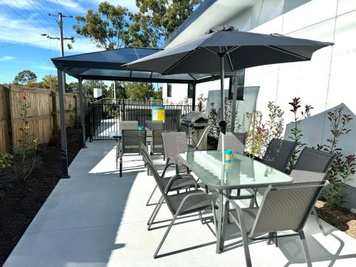 a patio with a table and chairs and an umbrella at Main Residences in Beenleigh