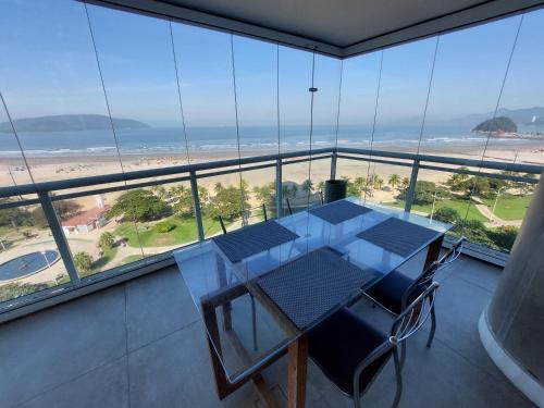 a table and chairs in a room with a view of the beach at Book Santos - Unlimited 901 - Frente Mar com Vista Panorâmica in Santos